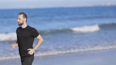 Athletic man running barefoot along the shoreline, enjoying his morning exercise by the sea