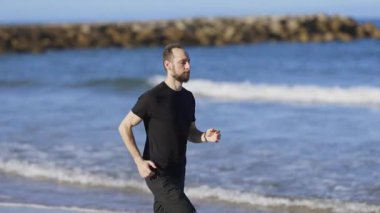 Sporty man jogging barefoot along the seashore for his daily fitness cardio exercise