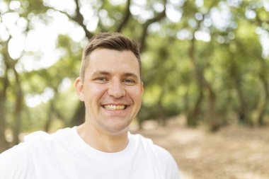 Man smiling in a park, showing happiness and positive emotions