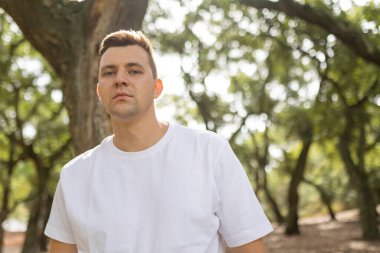 Young man standing outdoors, his direct gaze showing sincerity and individuality