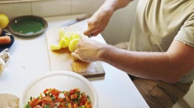 Cook expertly chops potatoes on a wooden cutting board, preparing ingredients for a delicious meal