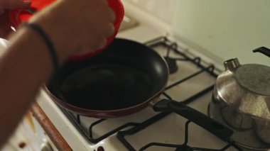 Close up of a mans hands preparing an omelette mixture in a red bowl in the kitchen