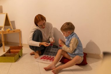 Ebeveyn ve çocuk yerde oturuyor, küçük yapı oyuncaklarını düzenleyiciden ayırıyorlar.