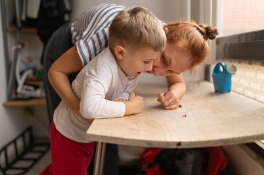 Küçük bir çocuk ve ebeveyn evdeki tahta bir yüzey üzerinde küçük bir böcek gözlemliyor.