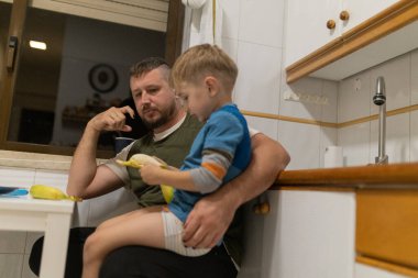 Oğlan sağlıklı beslenmek için muz soymayı öğrenirken baba oğul kaynaşıyor.