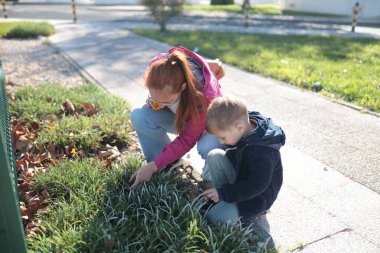 Kadın ve çocuk bir park ortamında çiçek ve bitkiler keşfediyor.