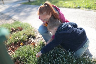 Kadın ve çocuk bir park ortamında çiçek ve bitkiler keşfediyor.