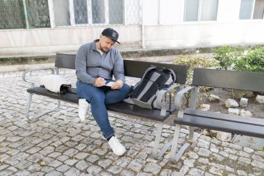 Şehir bankında otururken küçük bir defterde yazmaya odaklanan bir adam