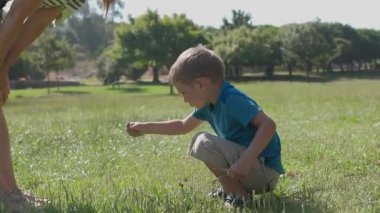 Genç bir çocuk çimen topluyor, annesine veriyor, ve sonra yeşil çimlerde koşuyor.