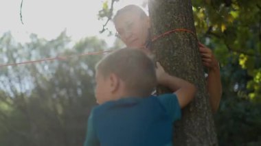 Mutlu bir aile, bir anne ve küçük oğlu, bir parktaki ağaç gövdesine ip bağlıyorlar.
