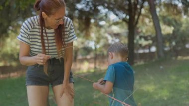 Genç anne, güneşli bir günde parkta oğluyla oynuyordu. Mutlu aile anlarının tadını çıkarıyordu.