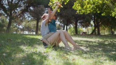 Mutlu anne ve küçük oğlu güneşli bir günde dışarıda oyuncak paraşütle oynuyorlar.