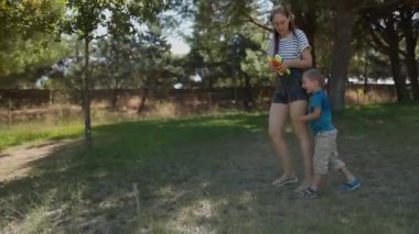Bir yaz parkında birlikte oynarken annesinin peşinde koşan küçük mutlu bir çocuk.