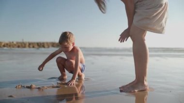 Mutlu aile, güneşli bir yaz tatili boyunca ıslak kumda birlikte vakit geçiriyor.