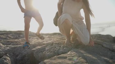 Genç anne ve küçük oğlu güneşli bir yaz akşamında kıyıya tırmanıp kayaları keşfediyorlar.