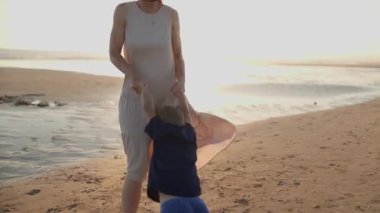 Mutlu anne ve oğul deniz kıyısında birlikte oynuyorlar, altın saat boyunca daireler çiziyorlar.