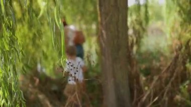 Sevgi dolu anne ve oğlu birlikte yemyeşil nehir kıyısını keşfederek bir yaz gününün tadını çıkarıyorlar.