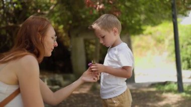 Mutlu aile doğada birlikte vakit geçiriyor, anne ve oğul parkta yürüyüş yapıyor.