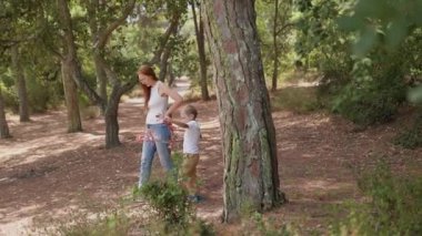 Küçük oğlum güneşli parkta yürürken annesine güzel bir kırmızı böğürtlen dalı uzatıyor.