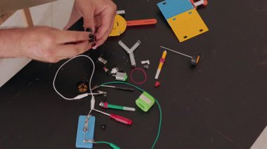 Erkek eller robot yaparken kabloları küçük bir elektrikli motora bağlıyor.