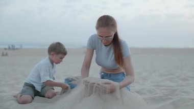 Mutlu anne ve küçük oğlu kumsalda birlikte oynayarak yaz tatilinin tadını çıkarıyorlar.