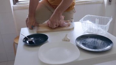 Erkek eller bıçakla bütün bir tavuğu kesiyor ve hazırlıyor.