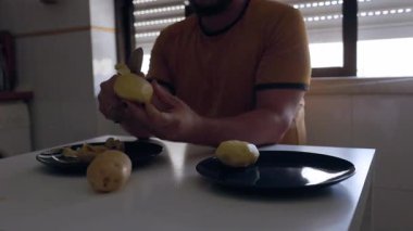 Masada oturan siyah ojeli bir adam mutfakta bıçakla patates soyuyordu.