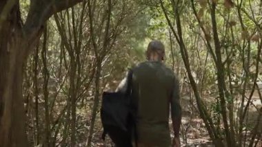 Sırt çantalı iki erkek arkadaş güneşli bir yaz gününde ormanda yürüyorlar.