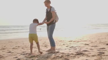 Deniz kıyısında yaz tatilinin tadını çıkarırken küçük oğlunu döndüren neşeli kadın.