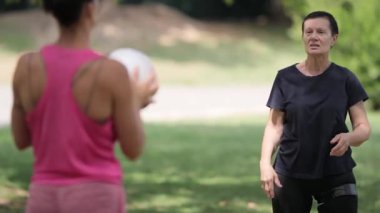 İki kadın parkta topla motor ve bilişsel rehabilitasyon egzersizleri yapıyor.