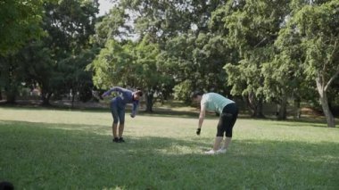 Aktif kadınlar şehir parkının yeşil çimlerinde ısınıp kaslarını esnetiyorlar.