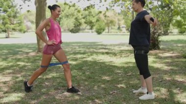 Genç bir kadın direniş bandıyla saldırırken kadın özel antrenörü ona yardım ediyor.