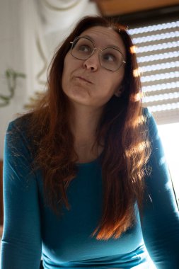 Yetişkin bir kadın dalgın dalgın bakıyor, kafasını kaldırıyor, bir fikir düşünüyor.