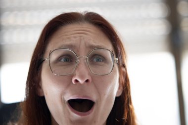 Güçlü bir şaşkınlık tepkisi gösteren bir kadın, gözleri tamamen açık ve ağzı açık.