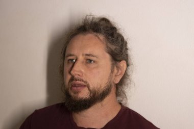 Sakallı ve çörekli bir adam sade bir arka plana karşı fikirler düşünüyor.