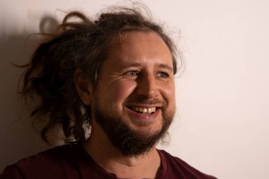 Rastalı ve sakallı adam gülüyor, neşe ve mutluluk ifade ediyor.