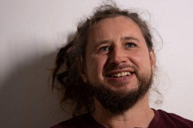 Sakallı ve rastalı mutlu bir adam yukarı bakıyor ve hafifçe gülümsüyor.