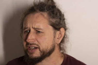 Sakallı, yüzünde endişe, stres ve endişe ifadesi olan genç bir adam.