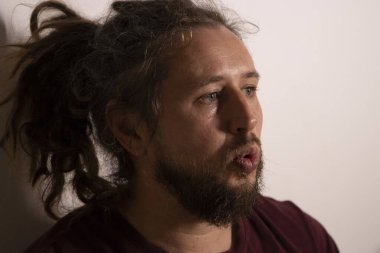 Sakallı ve rastalı bir adam bir şeye dikkatle bakıyor.