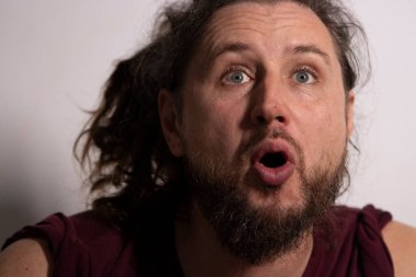 Sakallı ve uzun saçlı bir adam Şok ve merak içinde