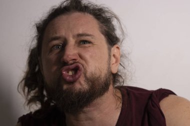 Adam komik bir ifade takınıyor, yüzünü buruşturuyor ve dudaklarını büzüyor.