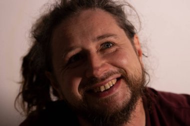 Sakallı, rastalı, neşe saçan, gülen ve başını kaldıran bir adam.