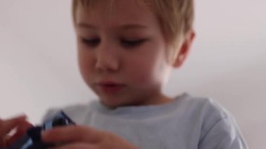 Küçük çocuk yoğun bir şekilde bir oyuncağa odaklanmış, çocukluk konsantrasyonu ve yaratıcı oyun sergiliyor.