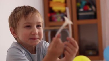 Sevimli küçük çocuk oyun odasında plastik bir oyuncakla oynarken kahkahalara boğuluyor.