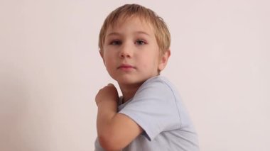 Sevimli küçük çocuk farklı komik suratlar yapıyor ve beyaz arka planda çeşitli duygular ifade ediyor.