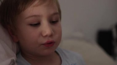 Sevimli küçük çocuk karanlık odasında uyumadan önce dijital tabletin keyfini çıkarıyor.