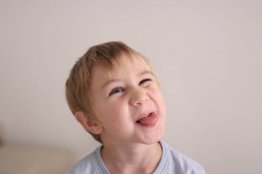 Küçük çocuk komik bir yüz ifadesiyle mizah ve küstahlık gösteriyor.