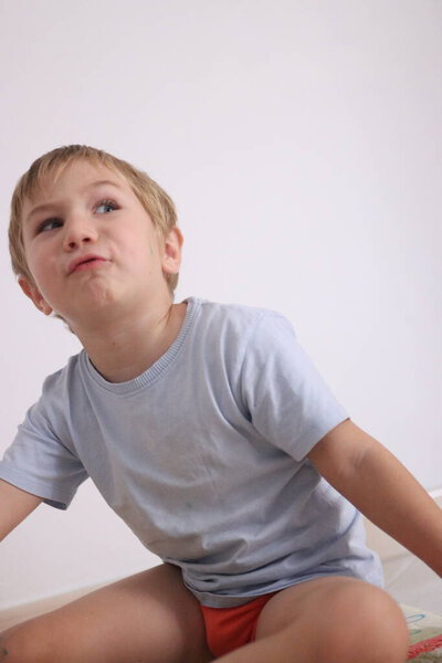 Young boy in casual clothes pulling a silly face while sitting indoors