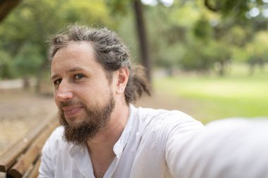 Açık havada kendi portresi için poz veren mutlu bir adam, boş zamanların tadını çıkarıyor.