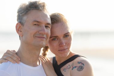 Mutlu çift dışarıda duruyor, kadın erkeğin omzunda dinleniyor, sevgi dolu bir anı paylaşıyor.